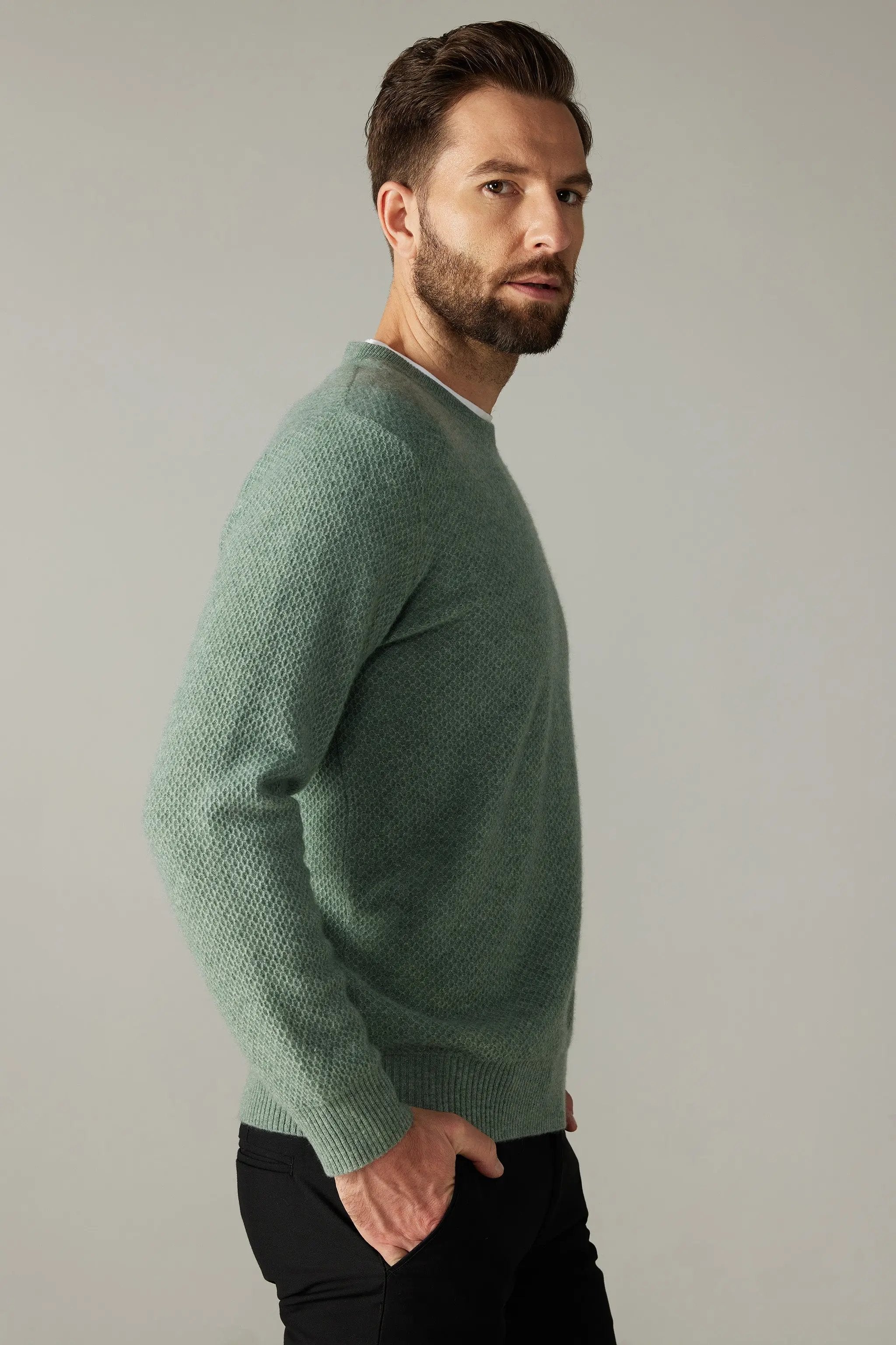 a man wearing a green sweater and black pants