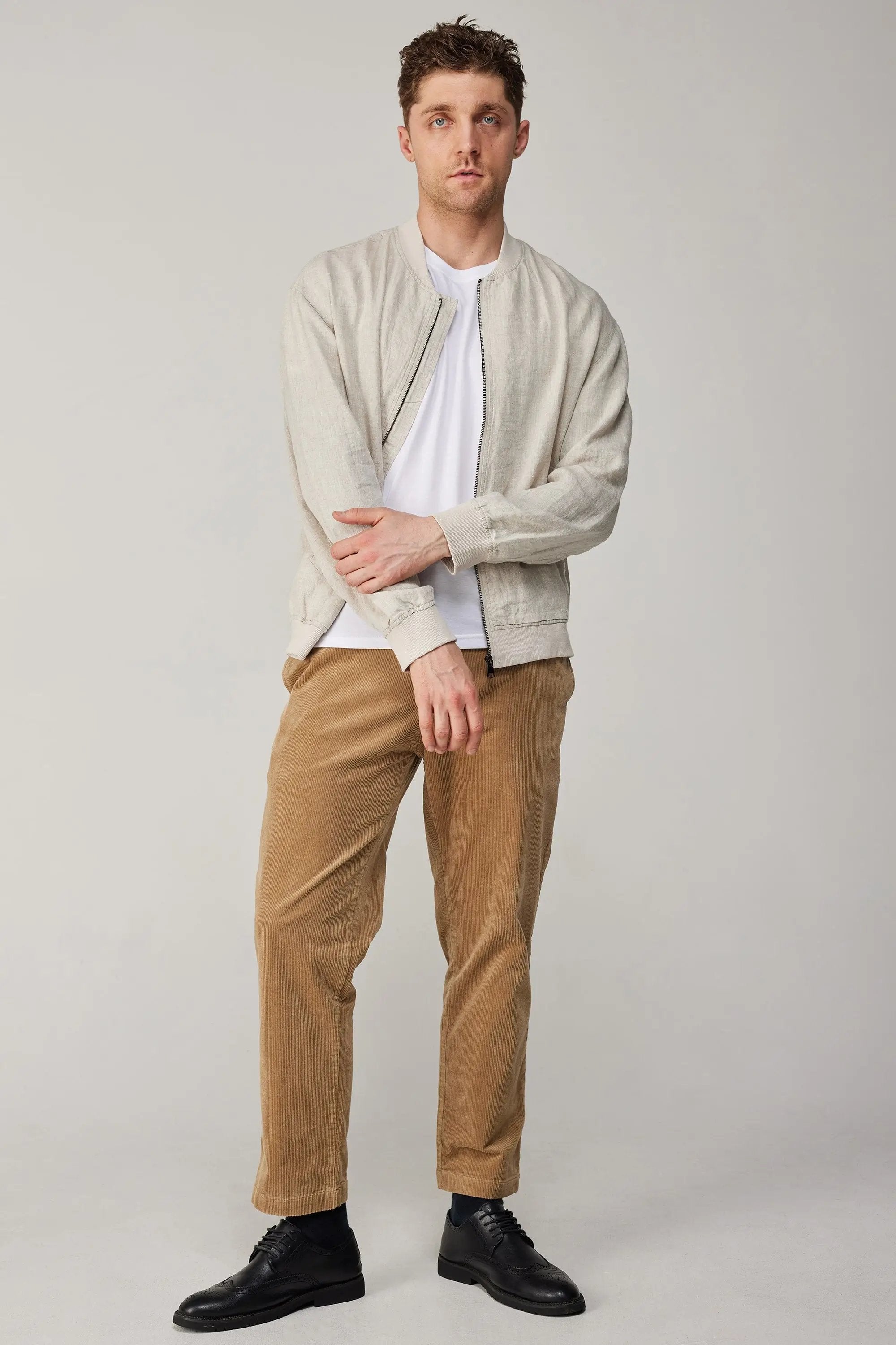 a man in a white shirt and brown pants