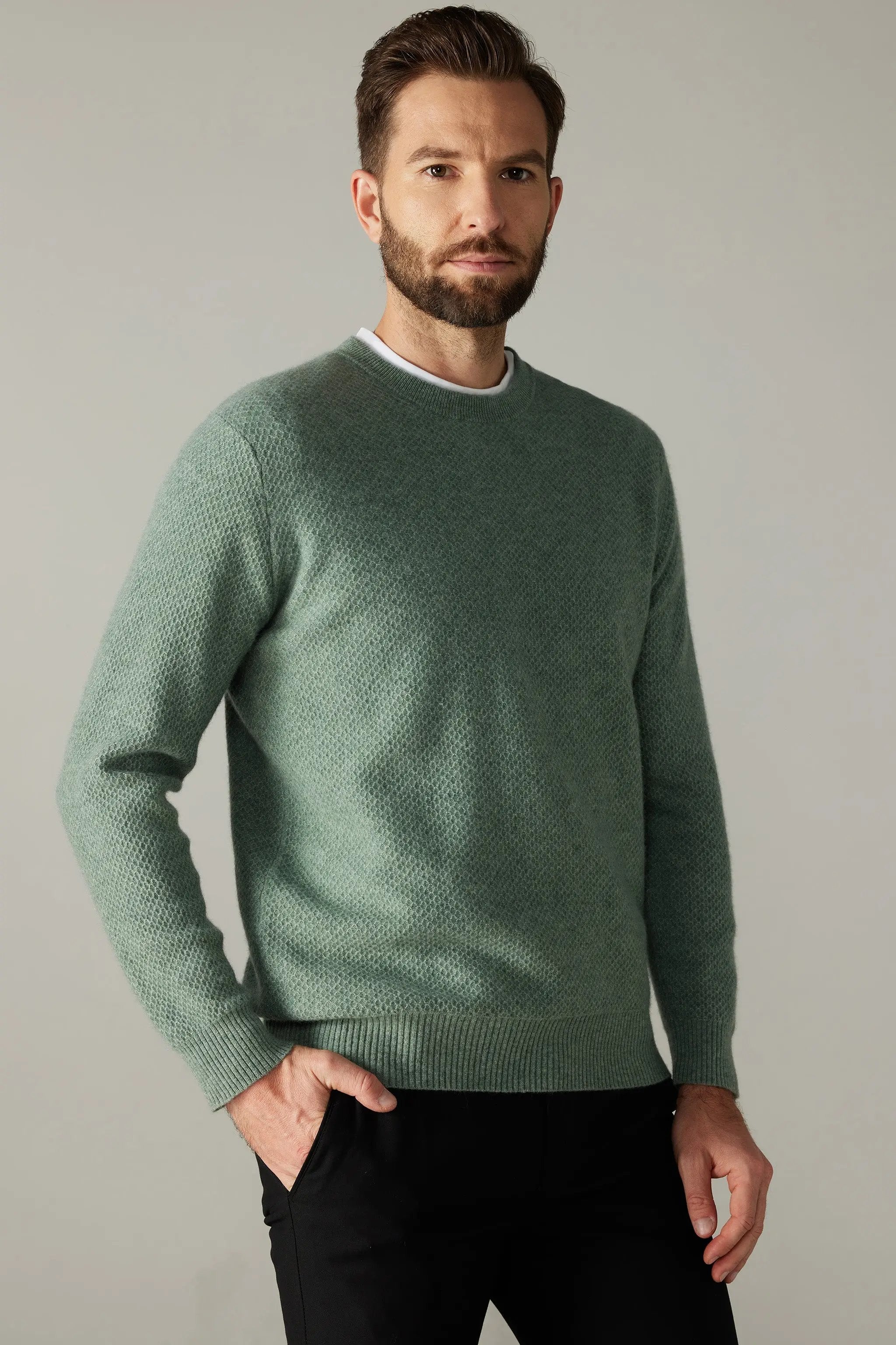 a man wearing a green sweater and black pants