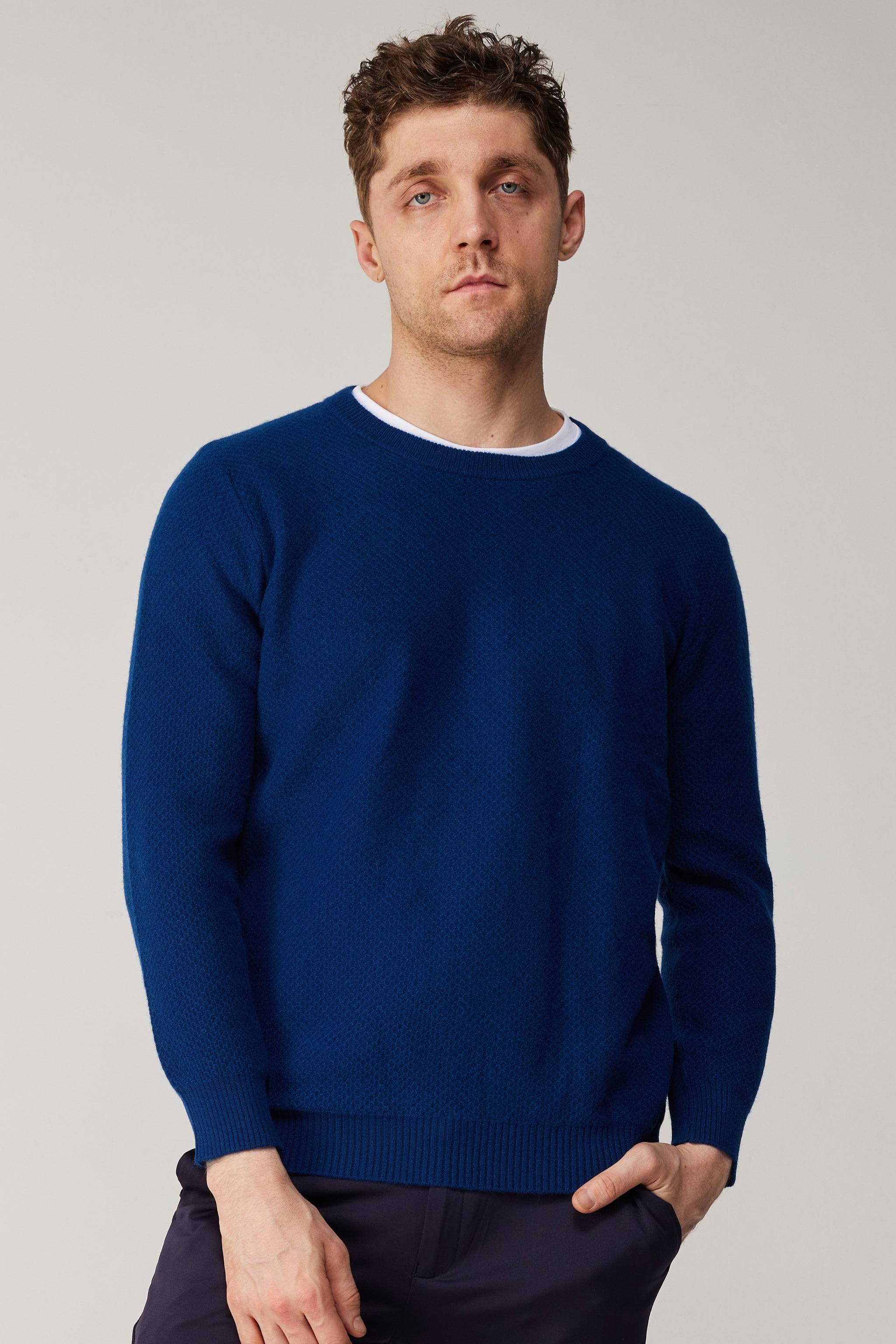 a man in a blue sweater is posing for a picture
