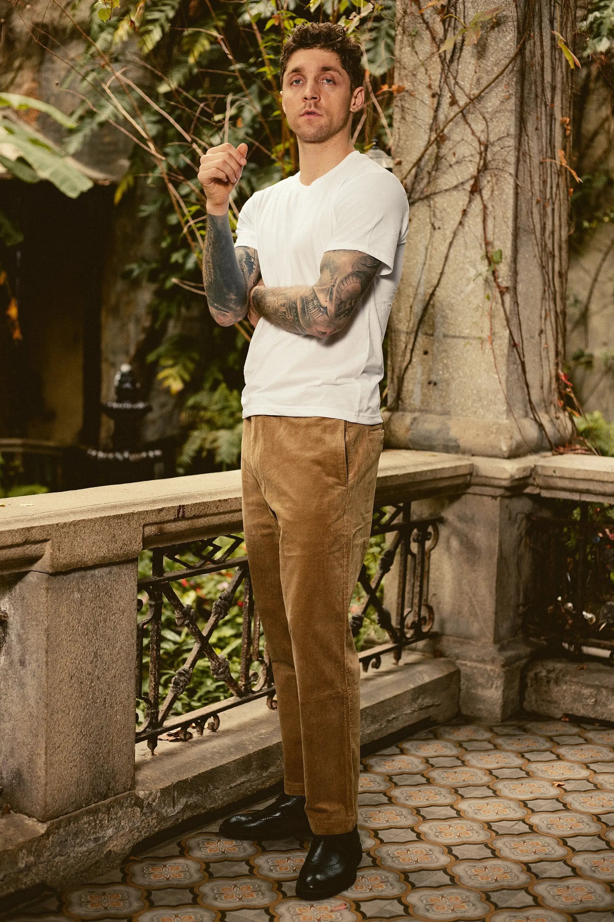 a man with a tattooed arm standing in front of a tree