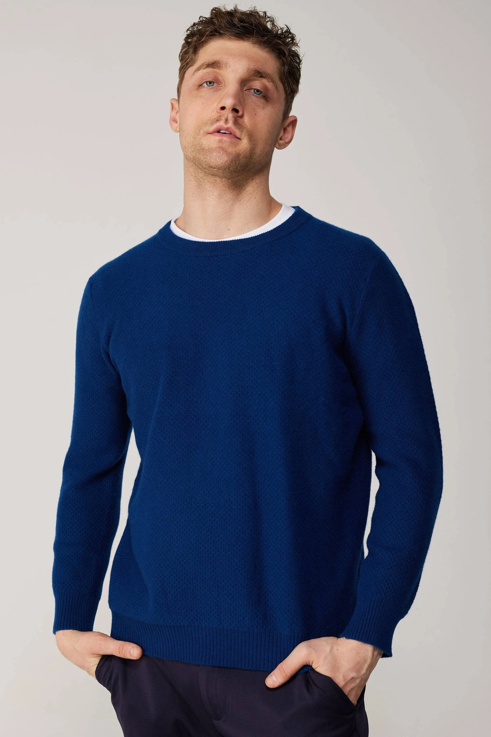 a man in a blue sweater poses for a picture