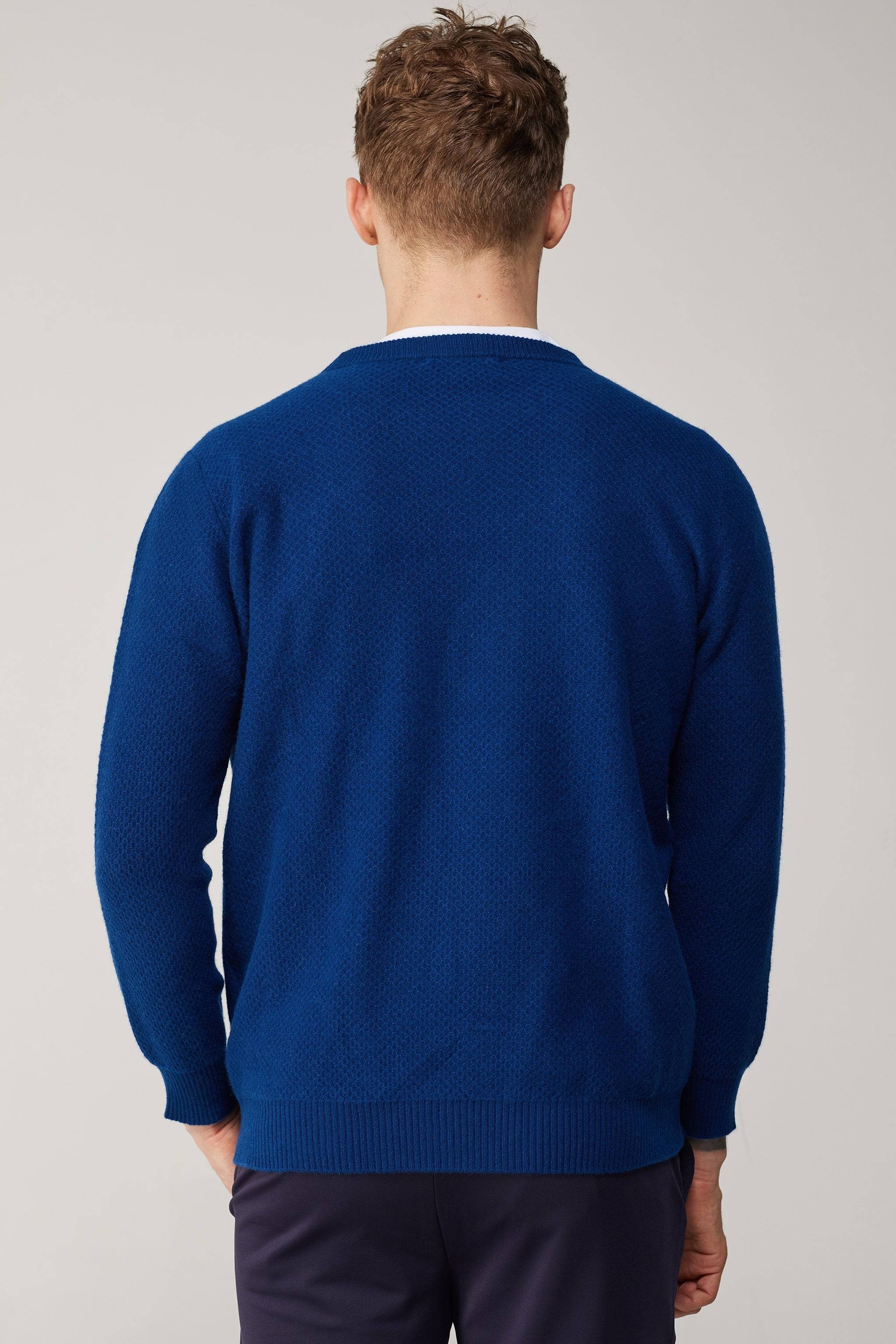 a man in a blue sweater is facing away from the camera