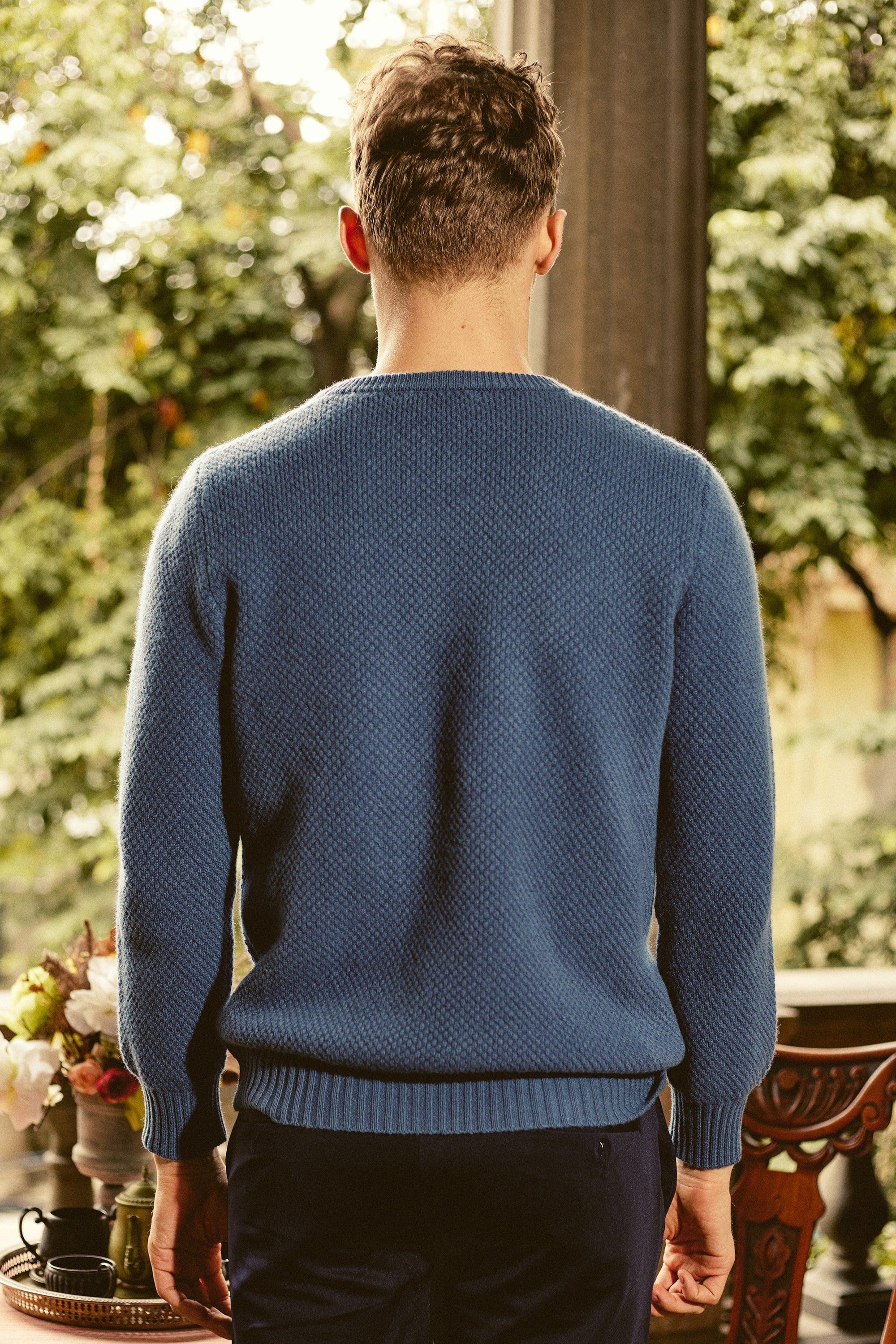 a man standing in front of a table wearing a blue sweater