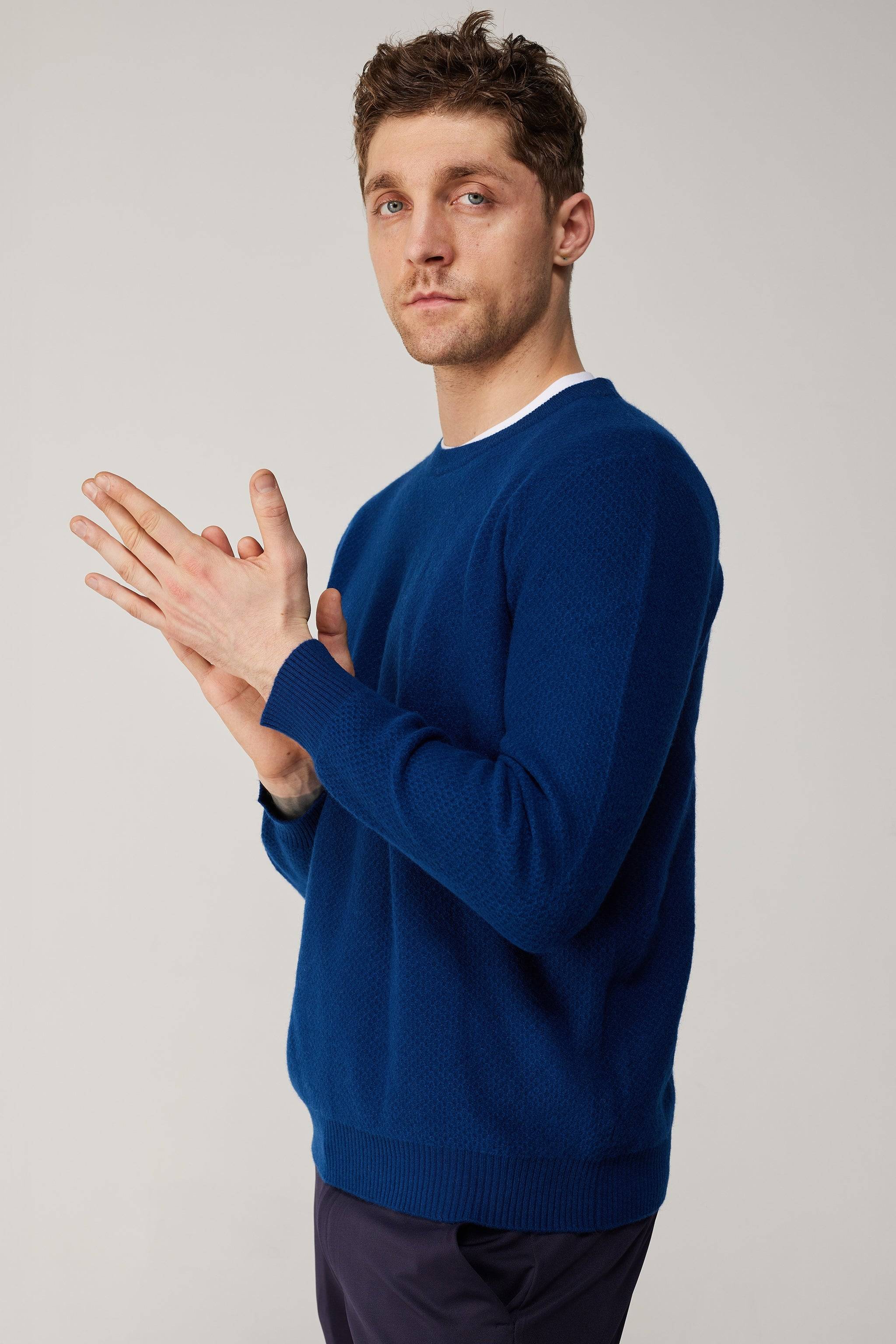 a man in a blue sweater is holding his hands together